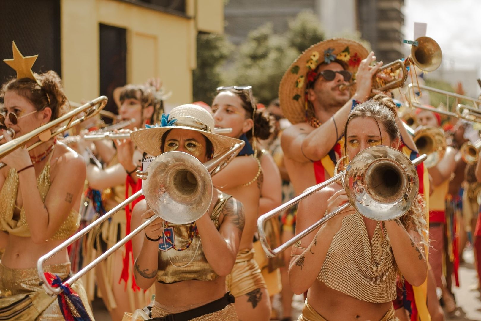Colorful carnival band members playing trombones and a trumpet