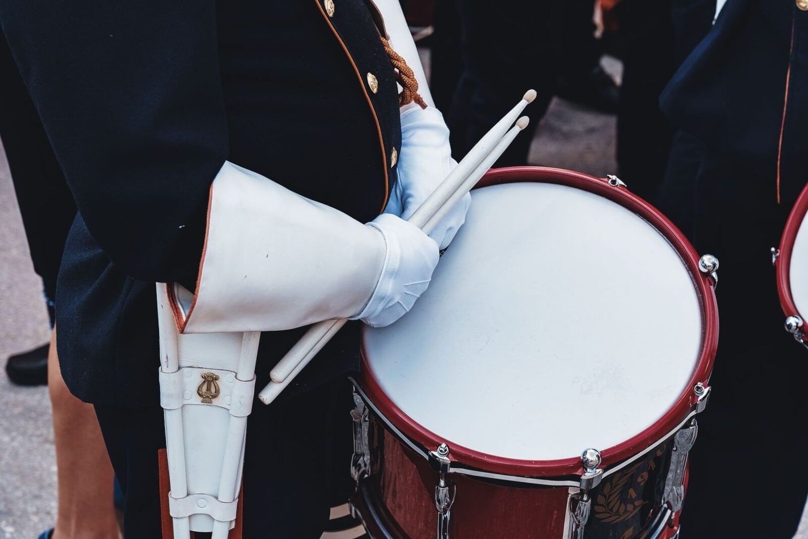Gloved marching-band drummer holding sticks over a large snare drum