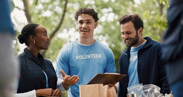 Volunteers discuss event tasks outdoors while holding a clipboard